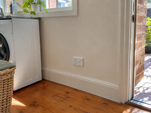 Double power point on a beige laundry wall above skirting beside a washing machine in Neutral Bay